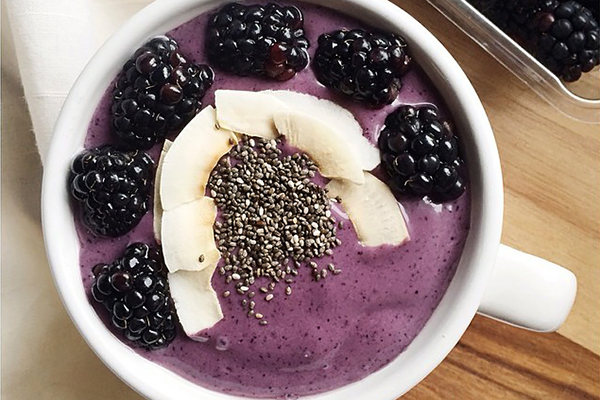 Mango, blueberry and acai protein smoothie bowl topped with blackberries, toasted coconut flakes and chia seeds. From wholeandhealthy.